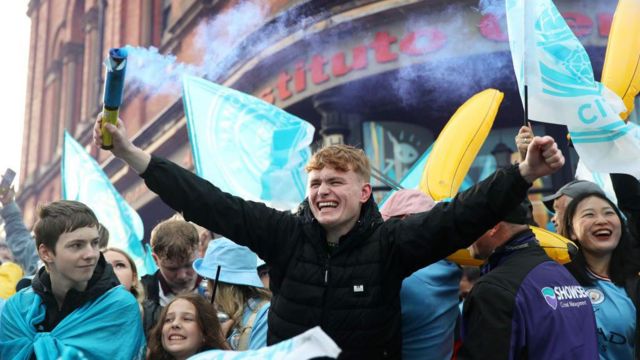 A fan of Manchester City is seen with a flare