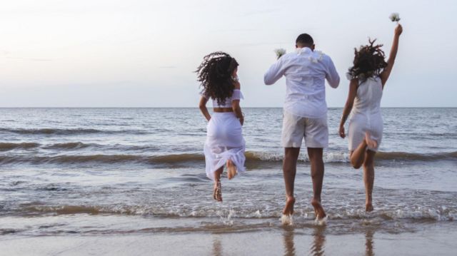 Pessoas pulando onda na praia vestidos de branco