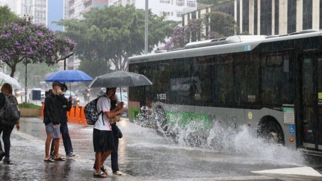 Pessoas com guarda-chuva em meio a forte chuva