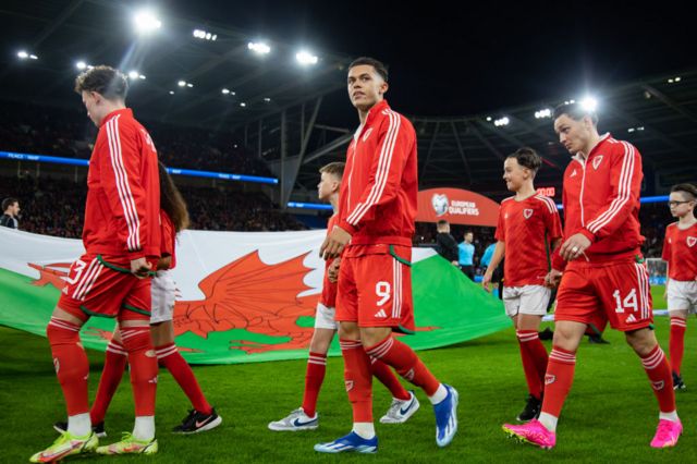 Brennan Johnson walks out on to the pitch with his Wales team-mates