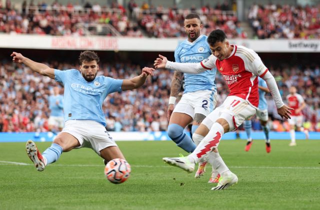Manchester City's Ruben Dias attempts to block a shot by Arsenal's Gabriel Martinelli