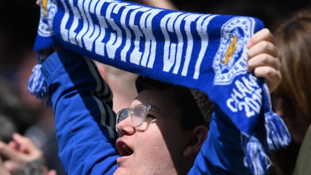 Leicester City fan holds up a scarf