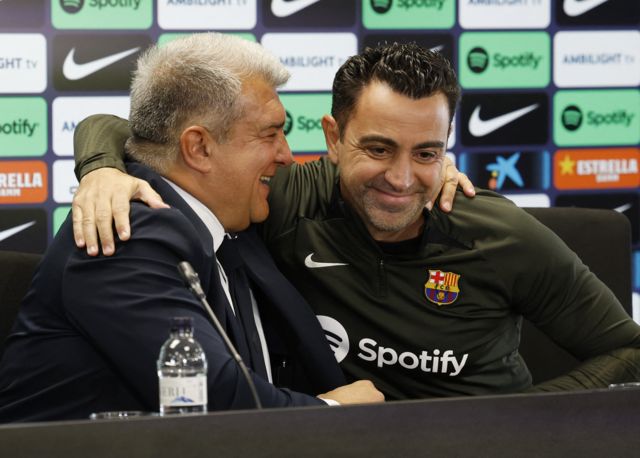 Barcelona president Joan Laporta hugs coach Xavi at a news conference