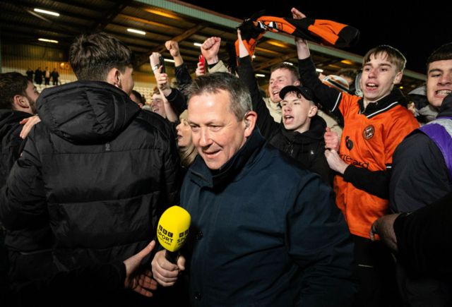 Billy Dodds is escorted away as Dundee United fans invade the pitch as they win the cinch Championship title during a cinch Championship match between Airdrionians and Dundee United at Excelsior Stadium, on April 26, 2024, in Airdrie, Scotland.
