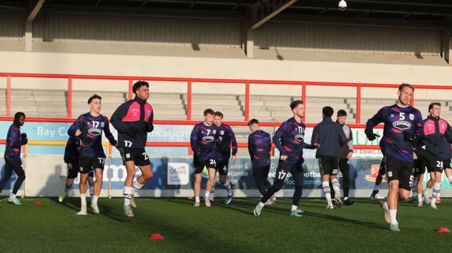 Crewe players warm up at Morecambe