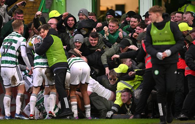 Paulo Bernardo of Celtic (partially obscured) celebrates with team mates after scoring their team's first goal as fans collapse