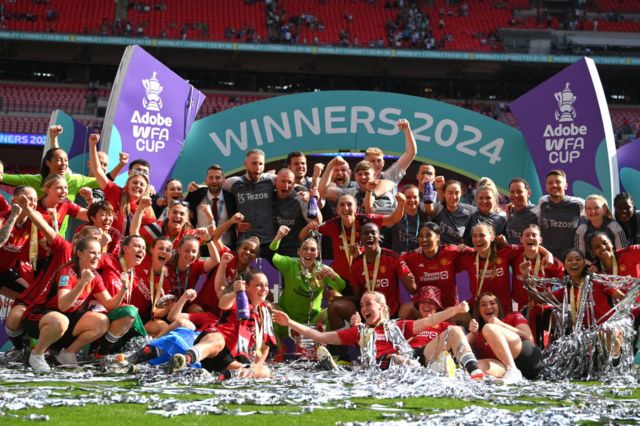 Players and staff of Manchester United pose with the Women's FA Cup Trophy after the team's victory in the Adobe Women's FA Cup Final match between Manchester United and Tottenham Hotspur