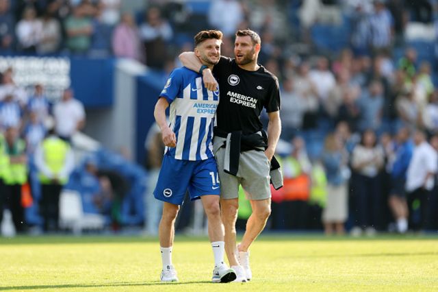 Adam Lallana of Brighton & Hove Albion is embraced by teammate James Milner