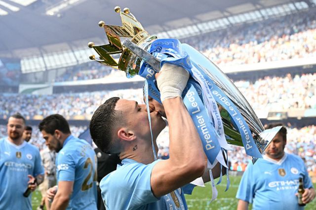 Phil Foden poses with the Premier League trophy
