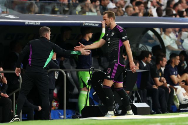 Kane high fives a coach as he walks to the bench