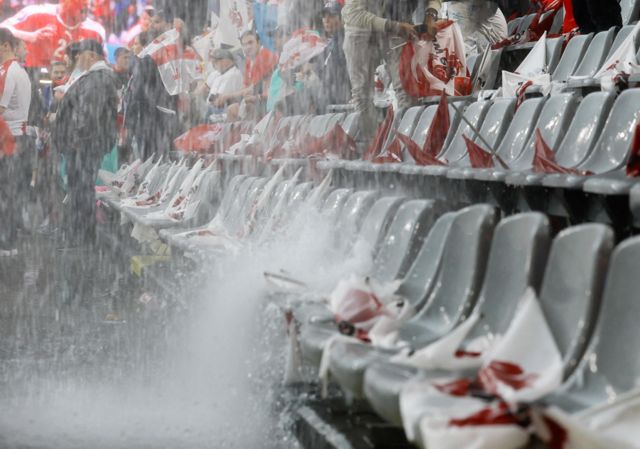 Water is pictured in the stands after falling from the roof due to heavy rain before the match