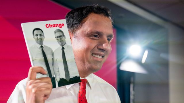 Scottish Labour leader Anas Sarwar holds up his party's manifesto, which has him and Kier Starmer on the cover with the words "change" in red.