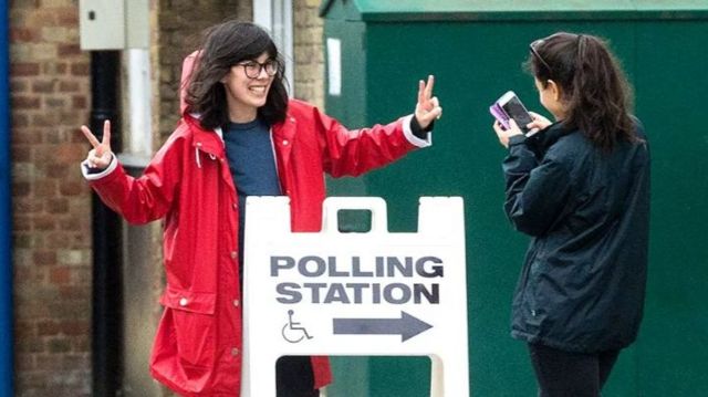 A person poses for a photo outside of a polling station