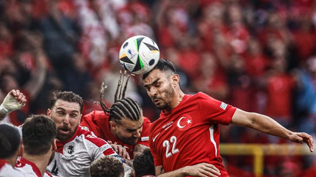 Kaan Ayhan (R) heads the ball