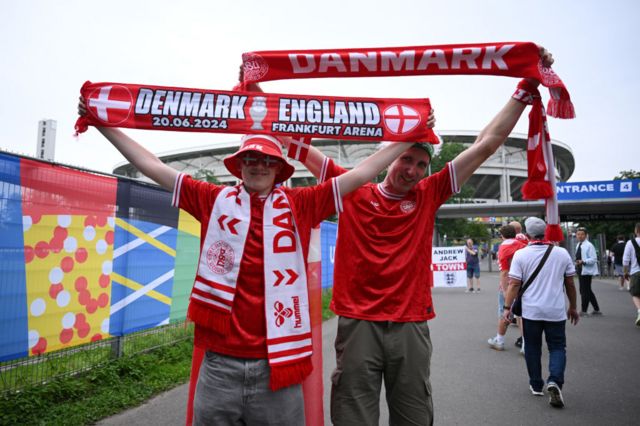 Denmark fans hold scraves above their heads outside the stadium