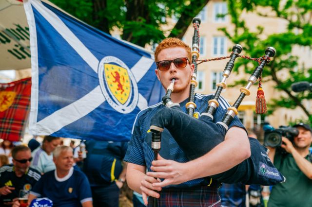 Scotland fan plays the bagpipes during a fan march
