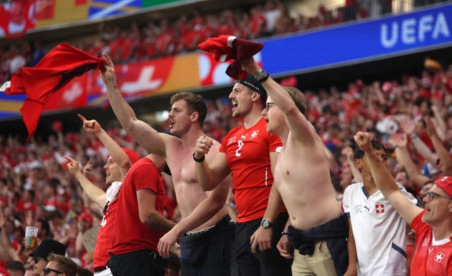 Swiss fans twirl their shirts around their heads