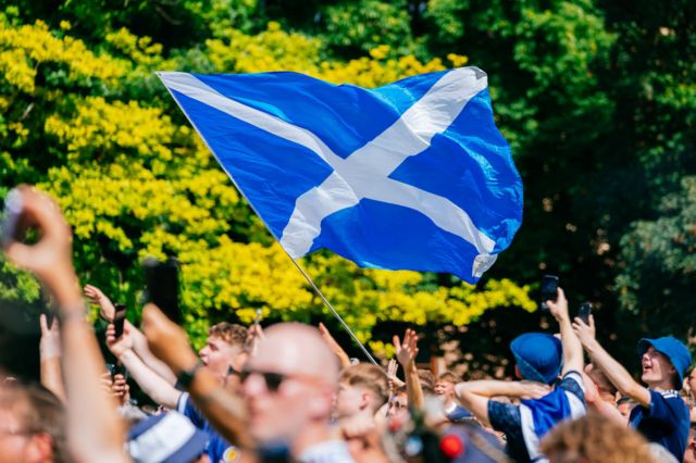 A Scotland flag flies above a crowd of Scotland fans in Stuttgart