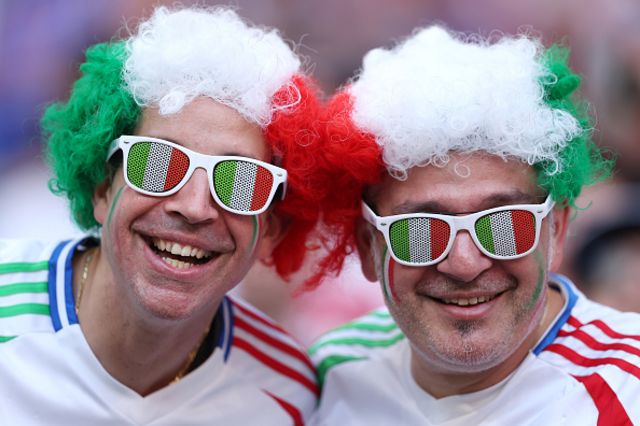 Fans of Italy pose for a photo whilst wearing wigs and sunglasses
