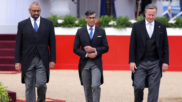 Stood in a row, from left to right, James Cleverly, Rishi Sunak, and David Cameron
