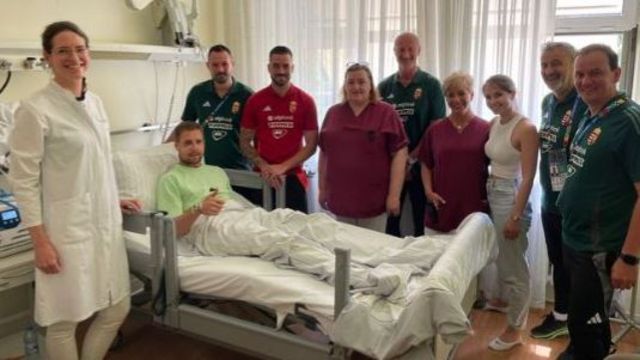 Hungary striker Barnabas Varga smiles and gives the thumbs-up in his hospital bed surrounded by staff and colleagues