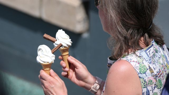 A lady holding two 99 ice creams