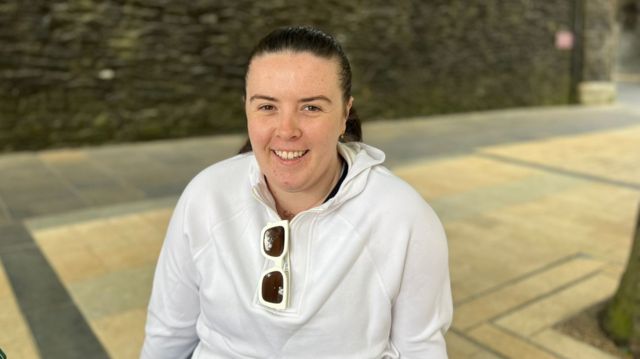 Orla, a female sitting down and wearing a white hoody