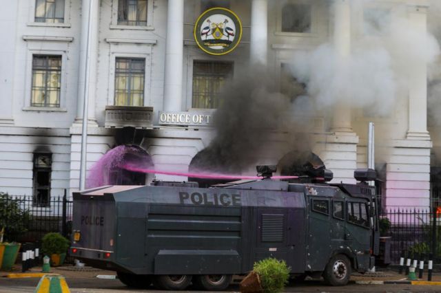 A police water cannon dampens a fire in the Office of the Governor near Parliament building