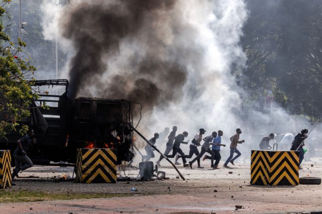 Protesters run to take cover outside the Kenyan Parliament after storming the building during a nationwide strike to protest against tax hikes and the Finance Bill 2024 in downtown Nairobi, on June 25, 2024.