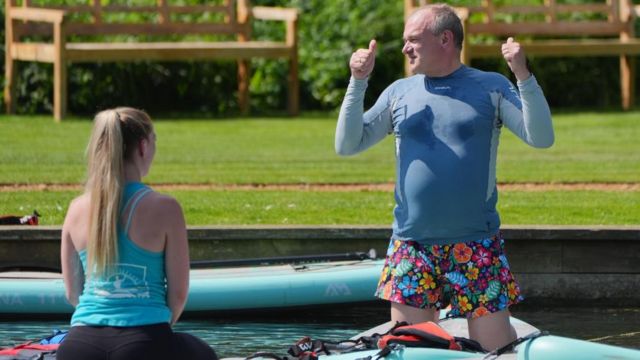 Sir Ed Davey takes part in paddleboard yoga during