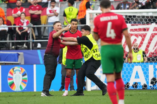 Cristiano Ronaldo on the pitch as a fan tries to take a selfie