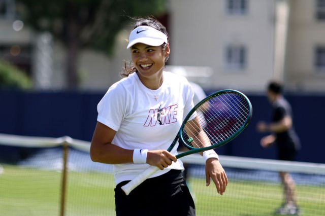 Emma Raducanu smiling with a tennis racquet in her hand