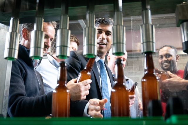 Sunak looks at bottles coming off a production line in a brewery