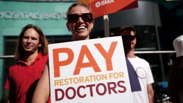 A person holds a sign calling for 'pay restoration for doctors'