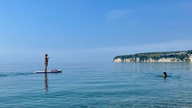 Paddleboarder and swimmer at Seaton beach in Devon