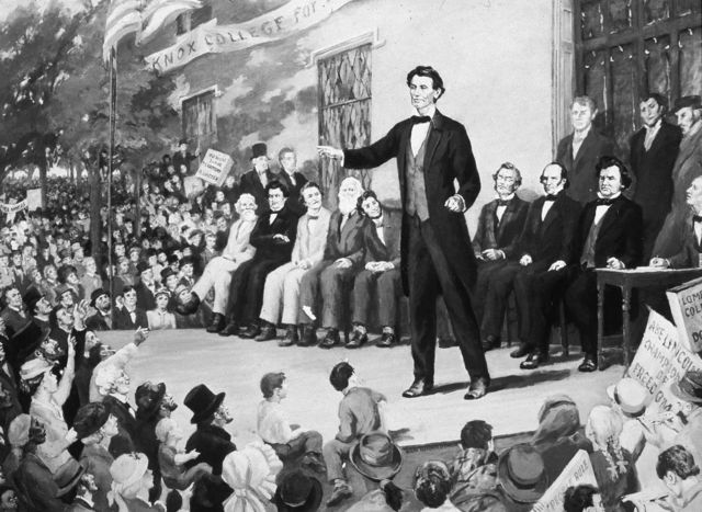 An illustration of Republican candidate Abraham Lincoln speaking on stage during a debate with Steven Douglas and other opponents at Knox College in Galesburg, Illinois on 7 October 1858