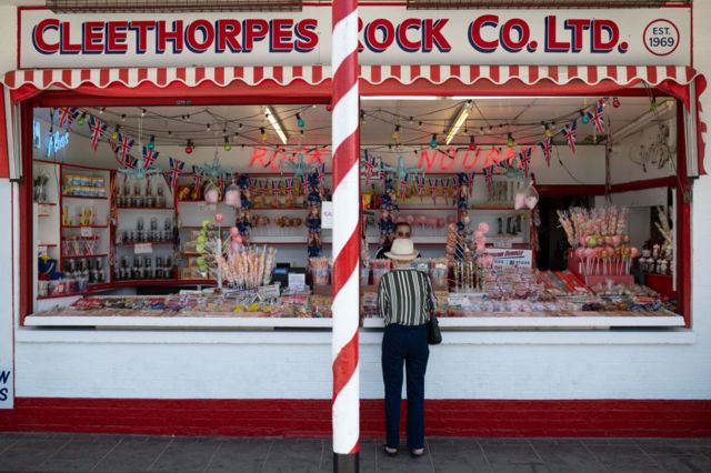 A woman buys goods at a shop called Cleethorpes Rock