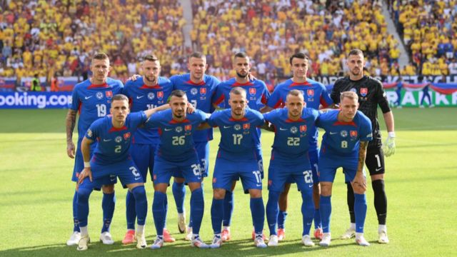 The Slovakia team together for a photo before playing Romania at Euro 2024.  They are all standing wearing a blue jersey with red trimming.