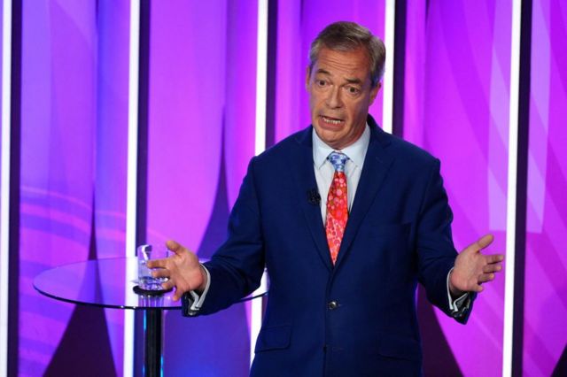 Reform UK leader Nigel Farage on stage with his hands in air as he talks
