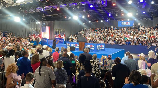 People cheer as they sit around a Biden Harris stage