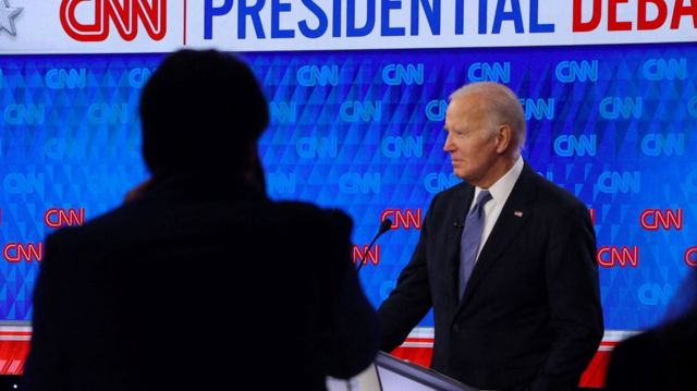 A photographer's shadow is seen next to President Biden on the debate stage in Atlanta