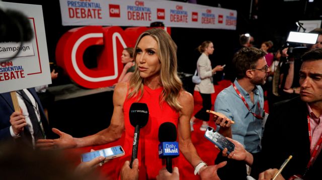 Lara Trump is photographed with a huddle of reporters surrounding her in the debate spin room
