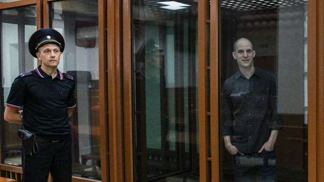 Wall Street Journal correspondent Evan Gershkovich, right, stands in a glass cage prior to a hearing in Russia on 26 June