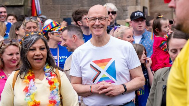 John Swinney at a Pride event wearing a t-shirt with the LGBTQ+ flag on it