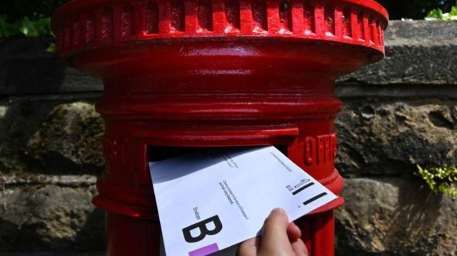 Postal vote being put into a red letter box