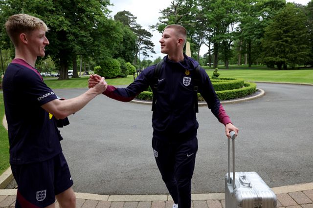 Anthony Gordon greets teammate Adam Wharton of England as he arrives