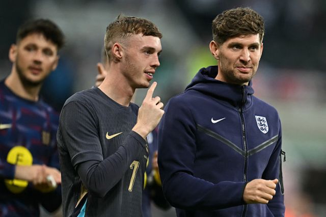 Cole Palmern (C) and England's defender John Stones walk on the pitch