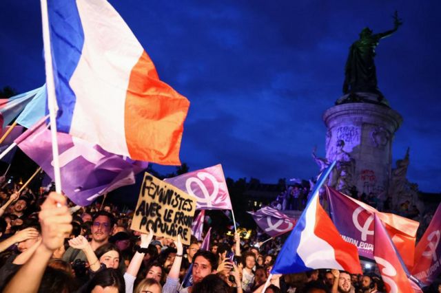 Demonstrators hold French flags and "Popular Union" flags in support of the Nouveau Front Populaire (New Popular Front - NFP) as they protest against the French far-right Rassemblement National (National Rally - RN) party, at the Place de la Republique in Paris, France, on 30 June 2024. The slogan reads "Feminists with the Popular Front"