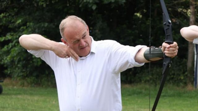 Sir Ed Davey trying archery, holding a crossbow