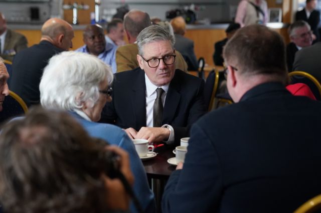 Sir Keir sits at a table with veterans at a coffee morning on the campaign trail